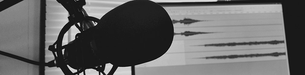 Fotografia de um estúdio com um microfone e um monitor de áudio.